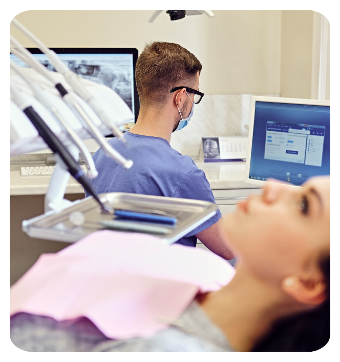 Odontólogo revisando historial clínico digital del paciente en ordenador en clínica dental en Barcelona.